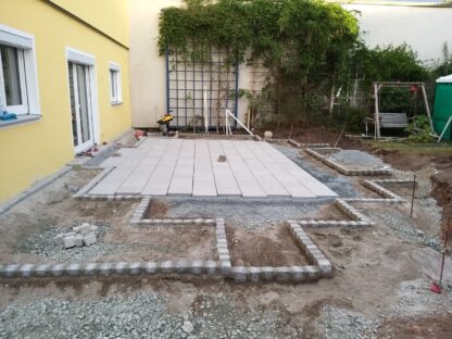 Terrasse mit diversen Pflanzbeeteinfassungen und Rasenfläche