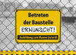 Yellow sign on fence saying: Entering the property prohibited. P